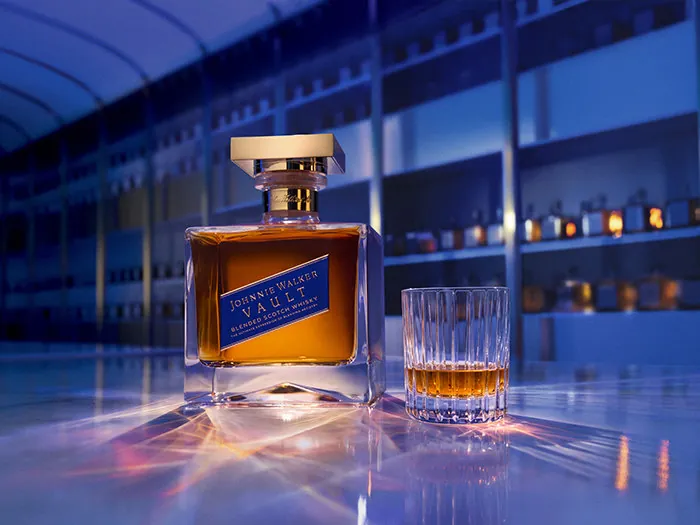Johnnie Walker Vault, whisky escocés blended: botella con tapón dorado junto a un vaso lleno