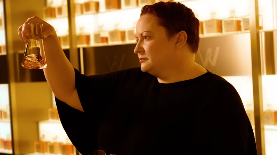 Johnnie Walker Vault: la maestra mezcladora Dr. Emma Walker examina una muestra de whisky en una copa ante estanterías iluminadas
