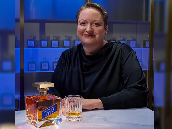 La Dr. Emma Walker, maestra mezcladora de Johnnie Walker, con una botella de Johnnie Walker Vault en una barra